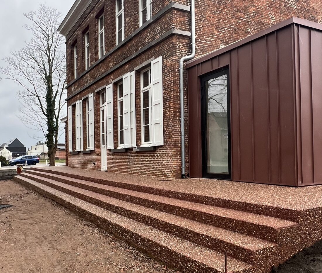 Op maat uitgevoerde trappen en terras in uitgewassen beton aan de pastorijwoning